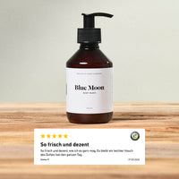 Blue Moon Body Wash 200 ml von Brooklyn Soap Company auf Holztisch, darunter eine Kundenbewertung mit 5 Sternen und dem Kommentar „So frisch und dezent“.