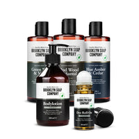 Körperpflege-Set für Männer von der Brooklyn Soap Company mit drei 2-in-1-Duschgels (Green Wood & Vetiver, Oud Wood & Santal, Blue Amber & Cedar), einer Bodylotion mit Muskatnuss und Zedernholz sowie einem Deo Roll-On mit Zedernholz und Citrus – für ein rundum gepflegtes Hautgefühl.